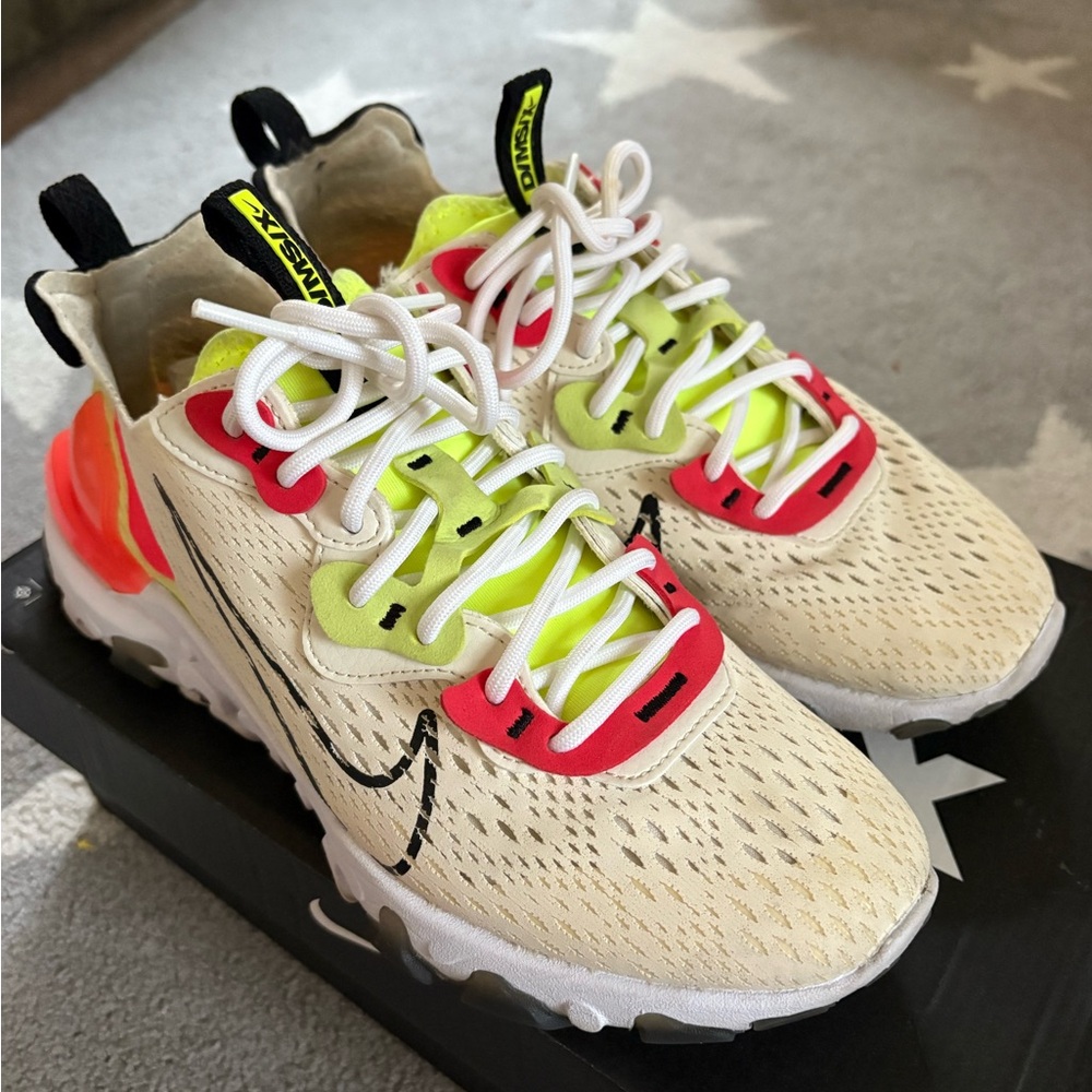 Nike React Vision D/MS/X sneakers in Pale Ivory, Black, Volt,and Laser Orange.